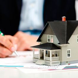 Casapaz maqueta de casa con persona firmando al fondo